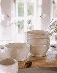 four white cereal bowls on wooden serving platter.