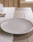 white ceramic dinner plate on wooden table with white table runner.