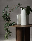 Stam cream white vase on wooden circle table.
