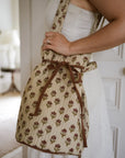 Drawstring duffle bag with tulips on, over a person's shoulder and tied up with a bow.