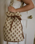 Drawstring duffle bag with tulips on, over a person's shoulder and tied up with a bow.