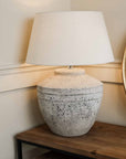 Large grey distressed lamp with white shade, switched on.