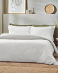 White waffle bedding set on double bed with green pillows.