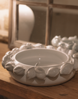 White ceramic bowl with decorative lemons on wooden table with mirror.