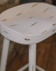 a detailed shot of white washed rustic wooden bar stool against stone wall.