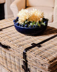 Wicker basket coffee table styled with blue bobble bowl with flowers in.