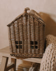 Woven basket with handle with chunky knitted throw on wooden bench.