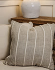 Striped neutral coloured square cushion on armchair.n