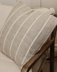 Striped neutral coloured square cushion from side view on armchair.n