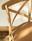 Close-up of a wooden chair with a cross-back design on a neutral background