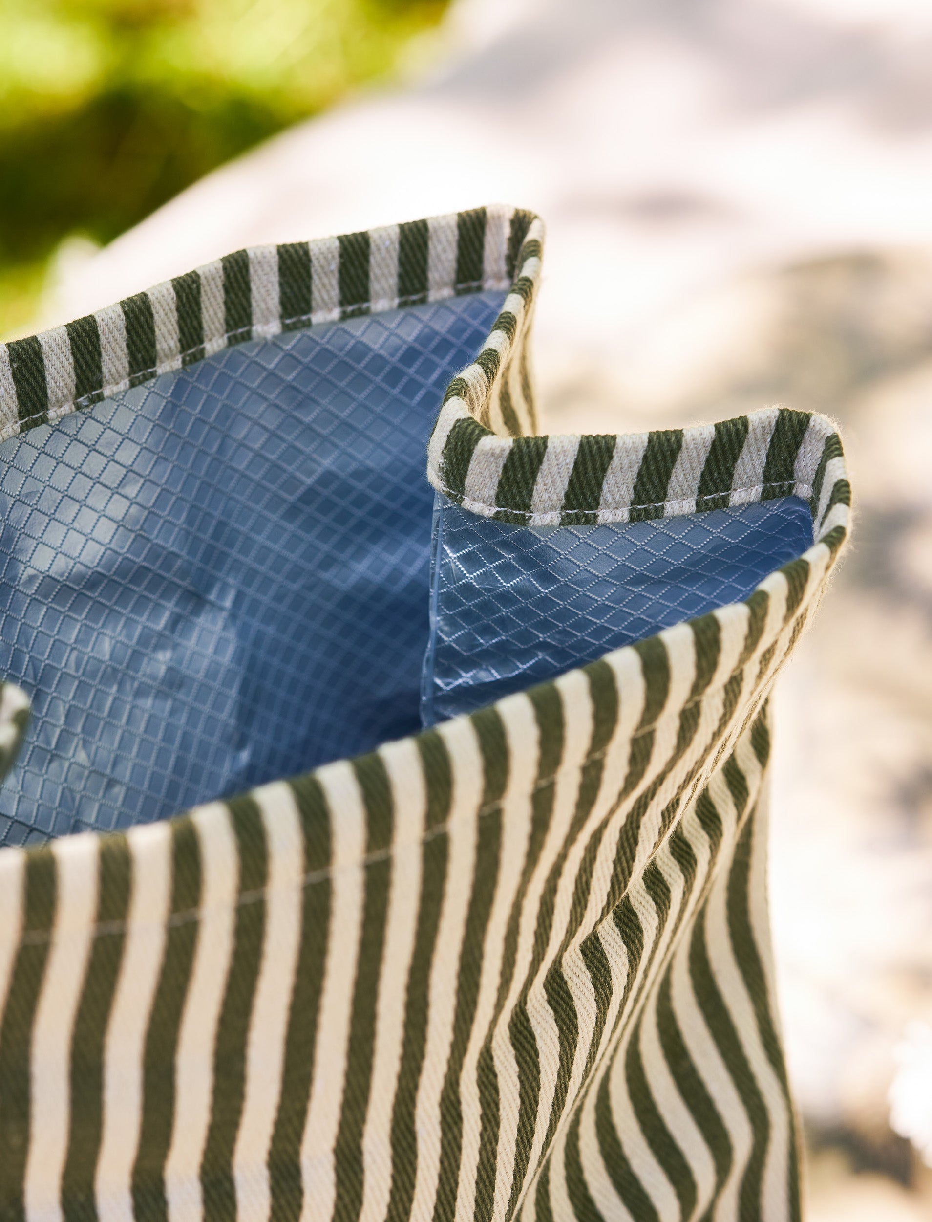 Close-up of a blue and green striped lunch bag with a blurred natural background