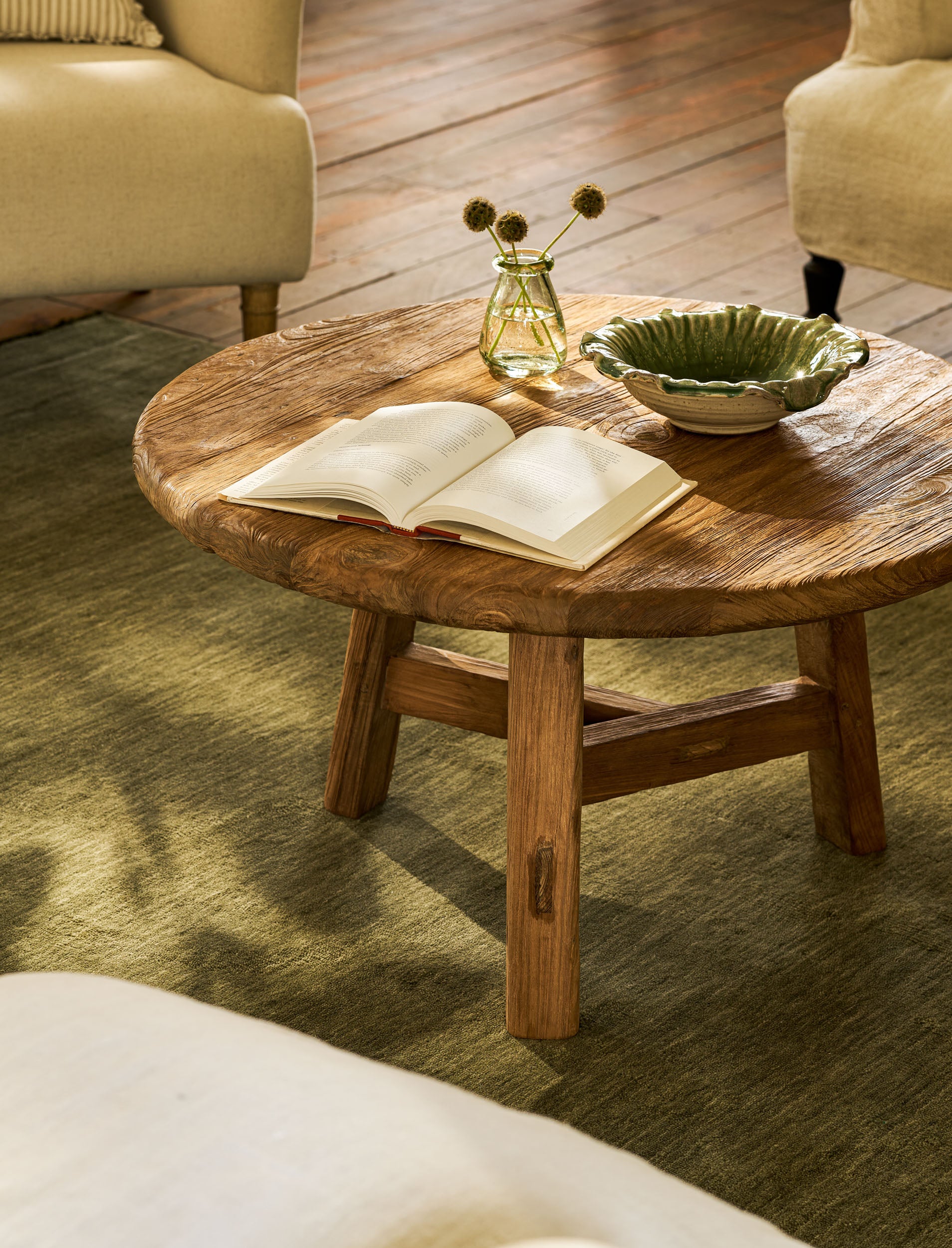 Wooden coffee table with an open book and decorative items in a living room setting.