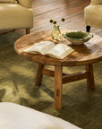 Wooden coffee table with an open book and decorative items in a living room setting.