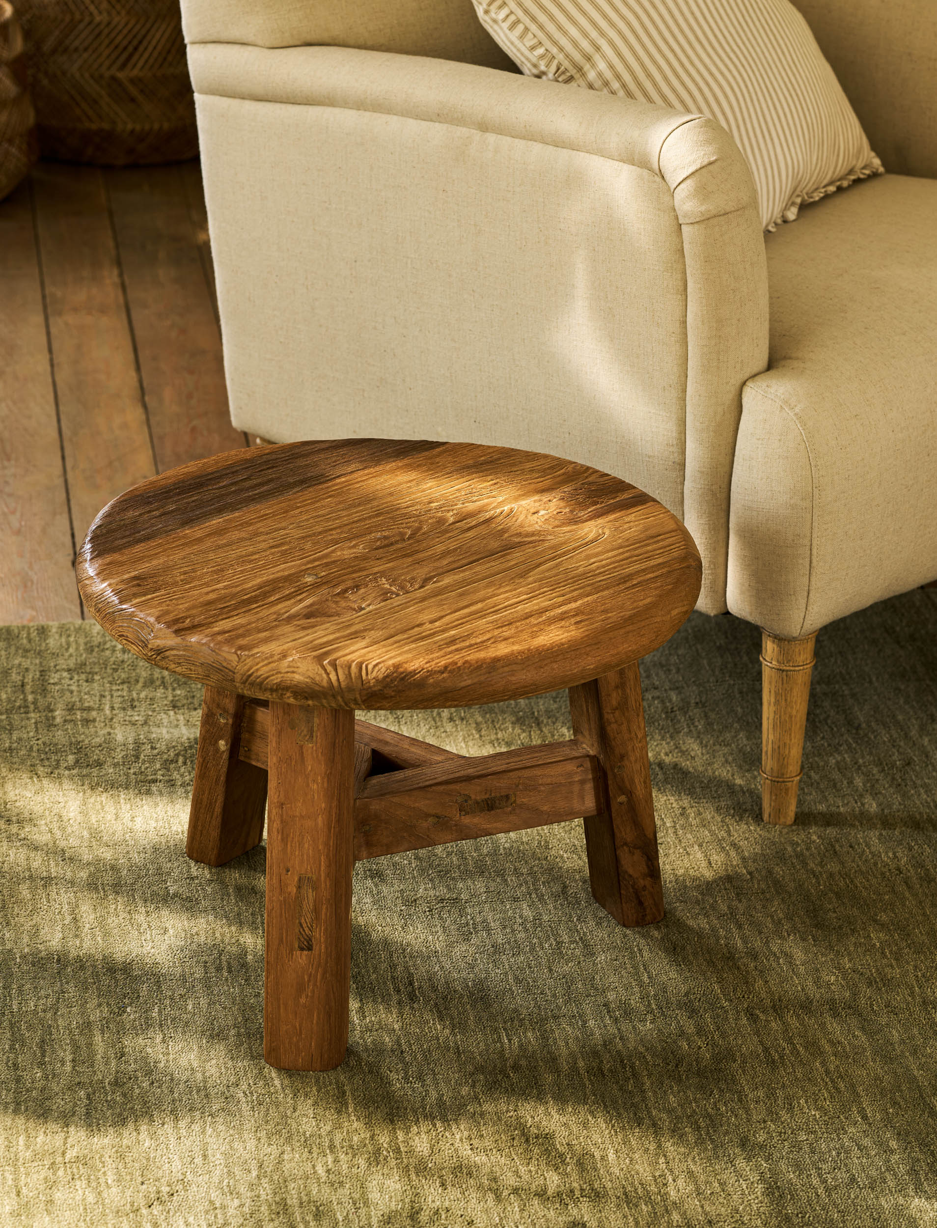 Round wooden table in front of a beige sofa on a carpeted floor