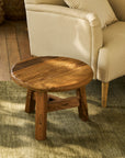 Round wooden table in front of a beige sofa on a carpeted floor