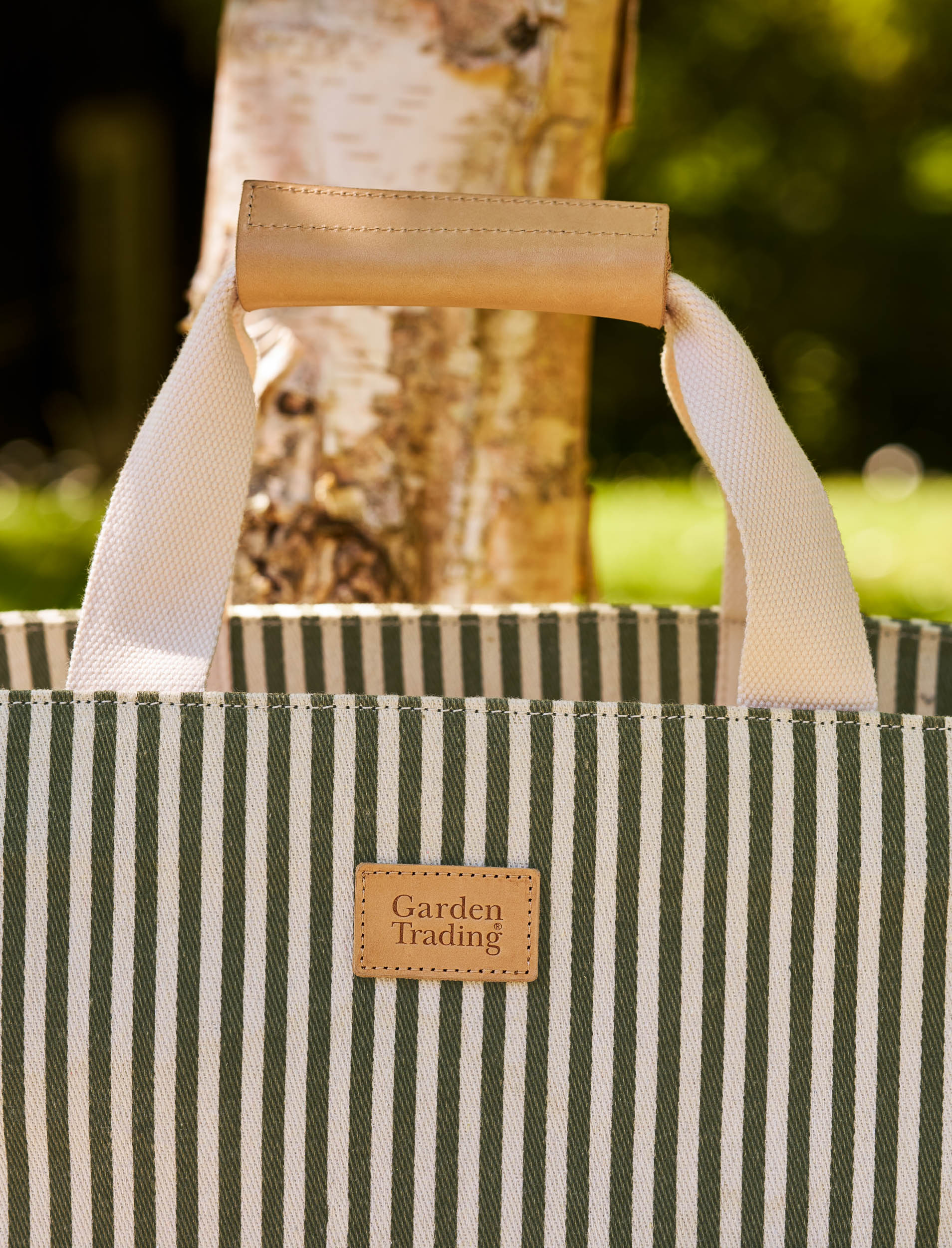 Striped picnic bag with 'Garden Trading' label against a blurred natural background