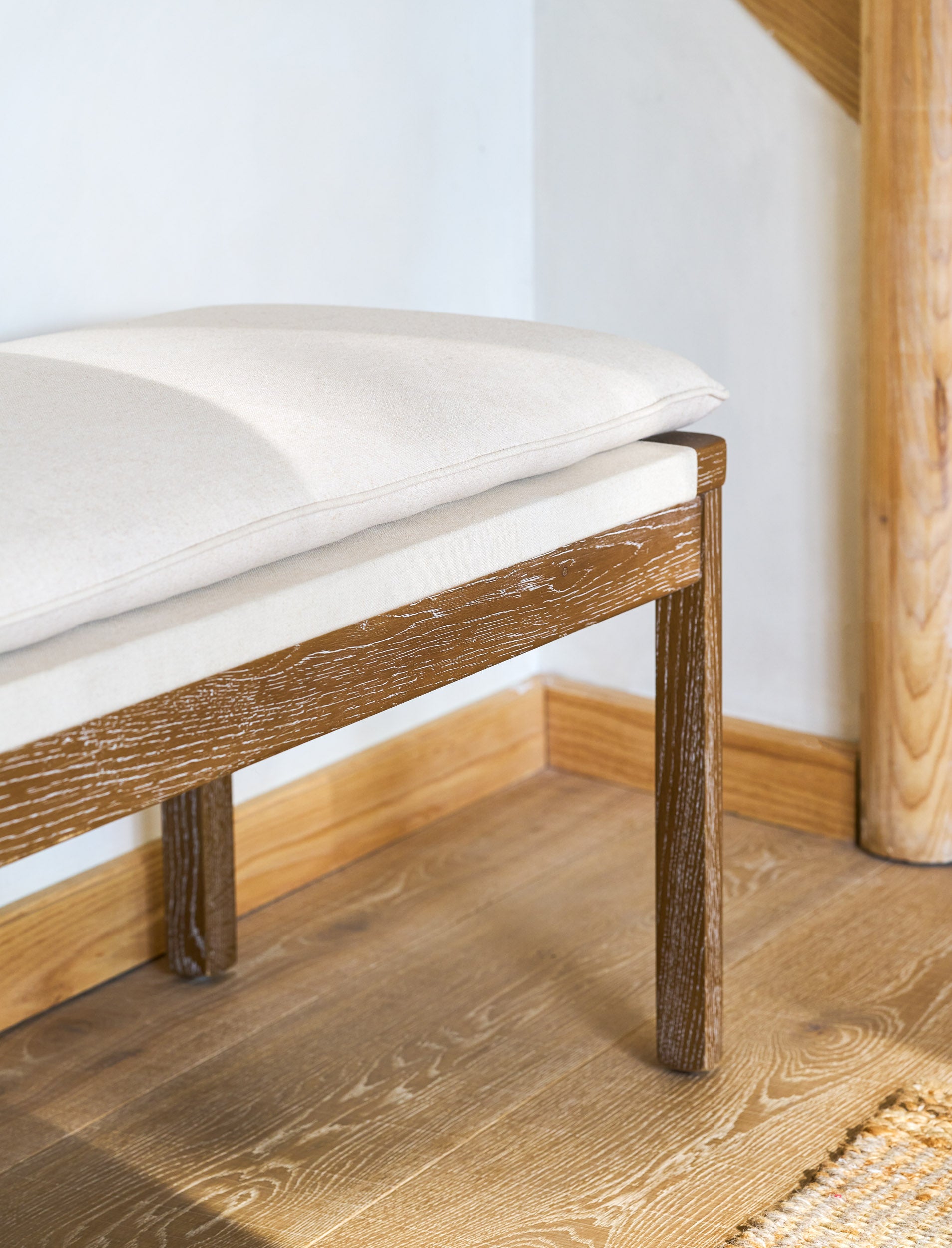 Wooden bench seating with cushions on a wooden floor.