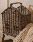 Woven basket with handle with chunky knitted throw on wooden bench.