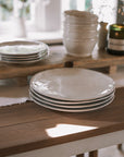 white ceramic dinner plates on wooden table with white table runner.