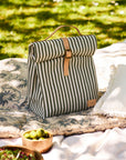 Striped lunch bag on a blanket with greenery in the background