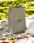 Striped lunch bag on a blanket with greenery in the background