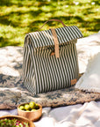 Striped lunch bag on a picnic blanket with greenery in the background