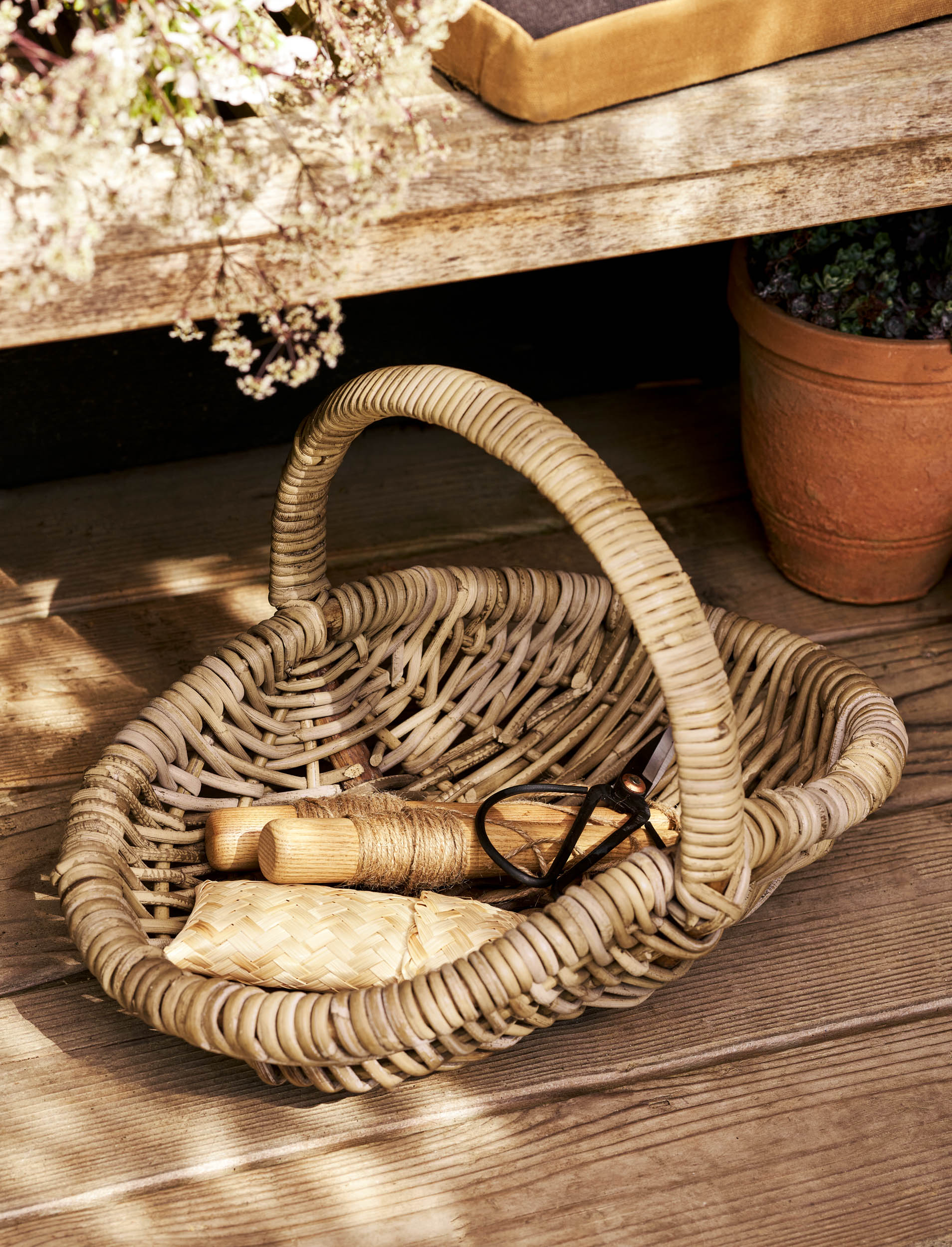 Rattan garden trug basket with items on a wooden surface