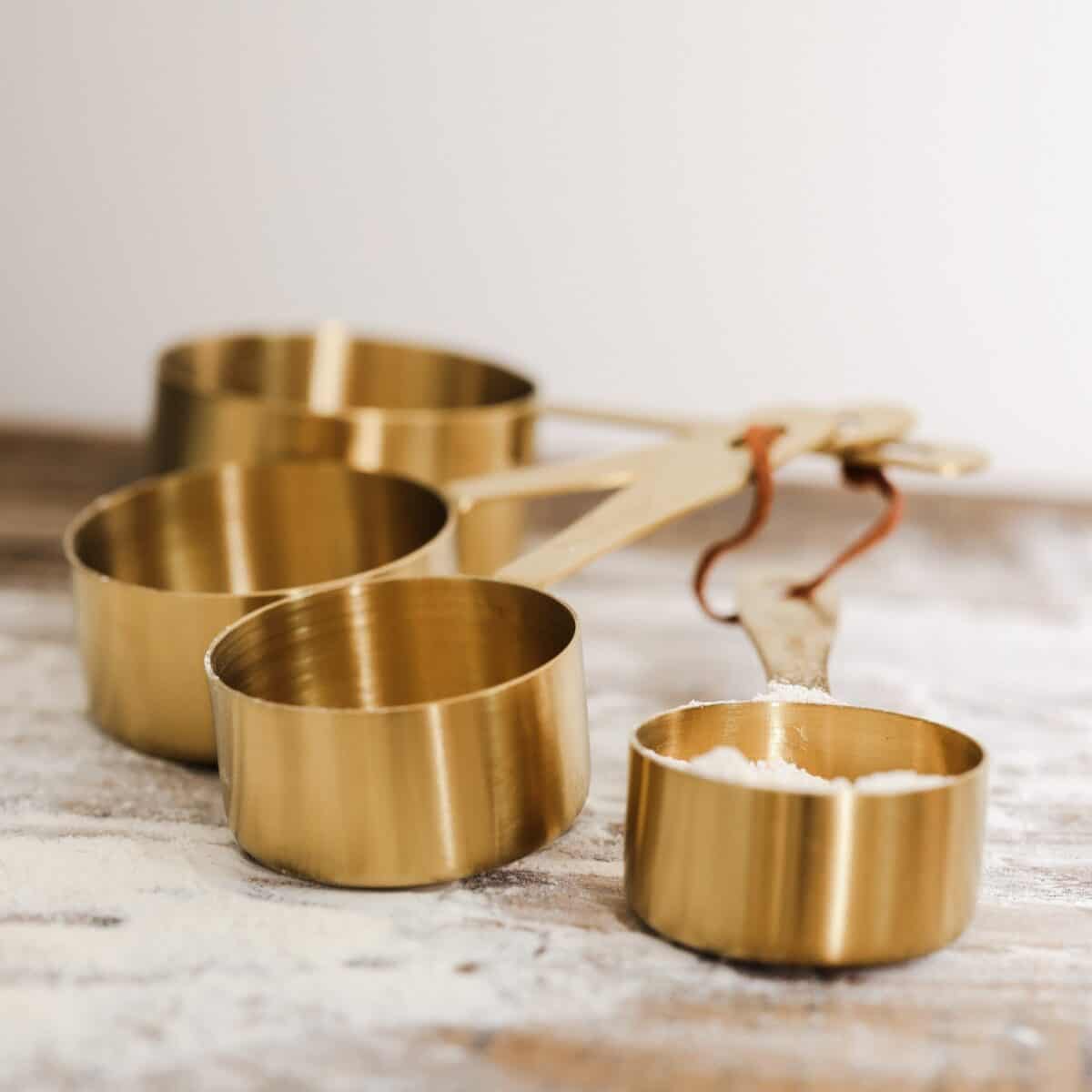 Measuring Cups filled with sugar on a floured surface.