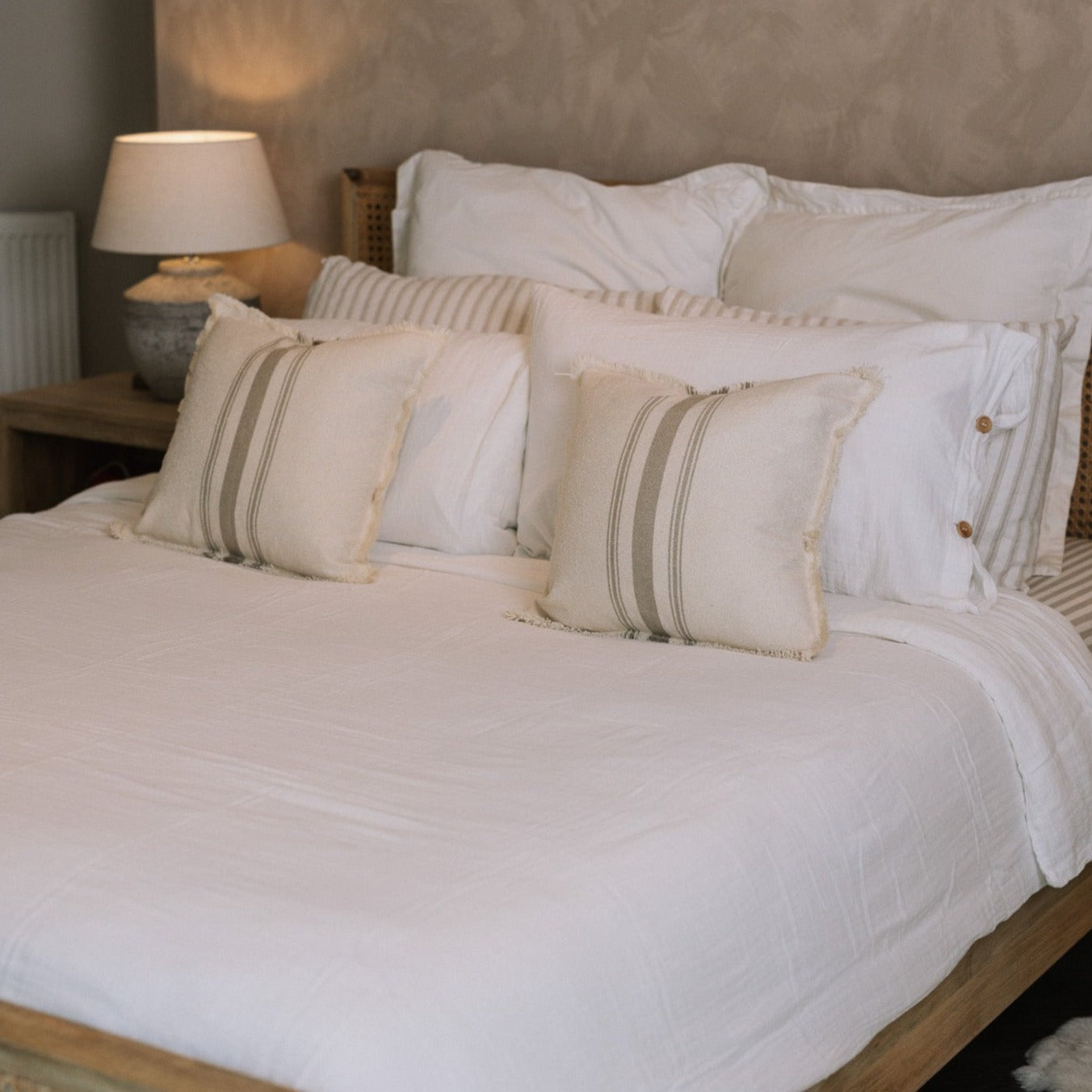 White muslin bedding set with striped cushions.