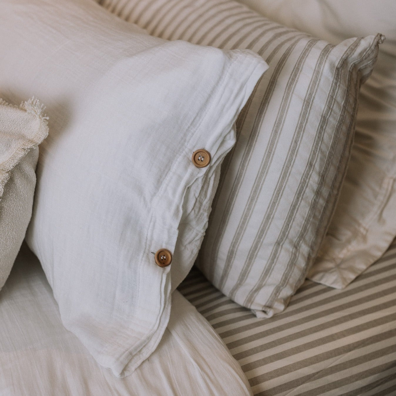 White and striped bedding with wooden button detailing.