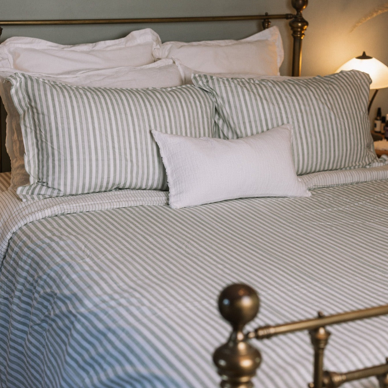 Green striped bedding on a brass bed.