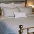 Green striped bedding on a brass bed.