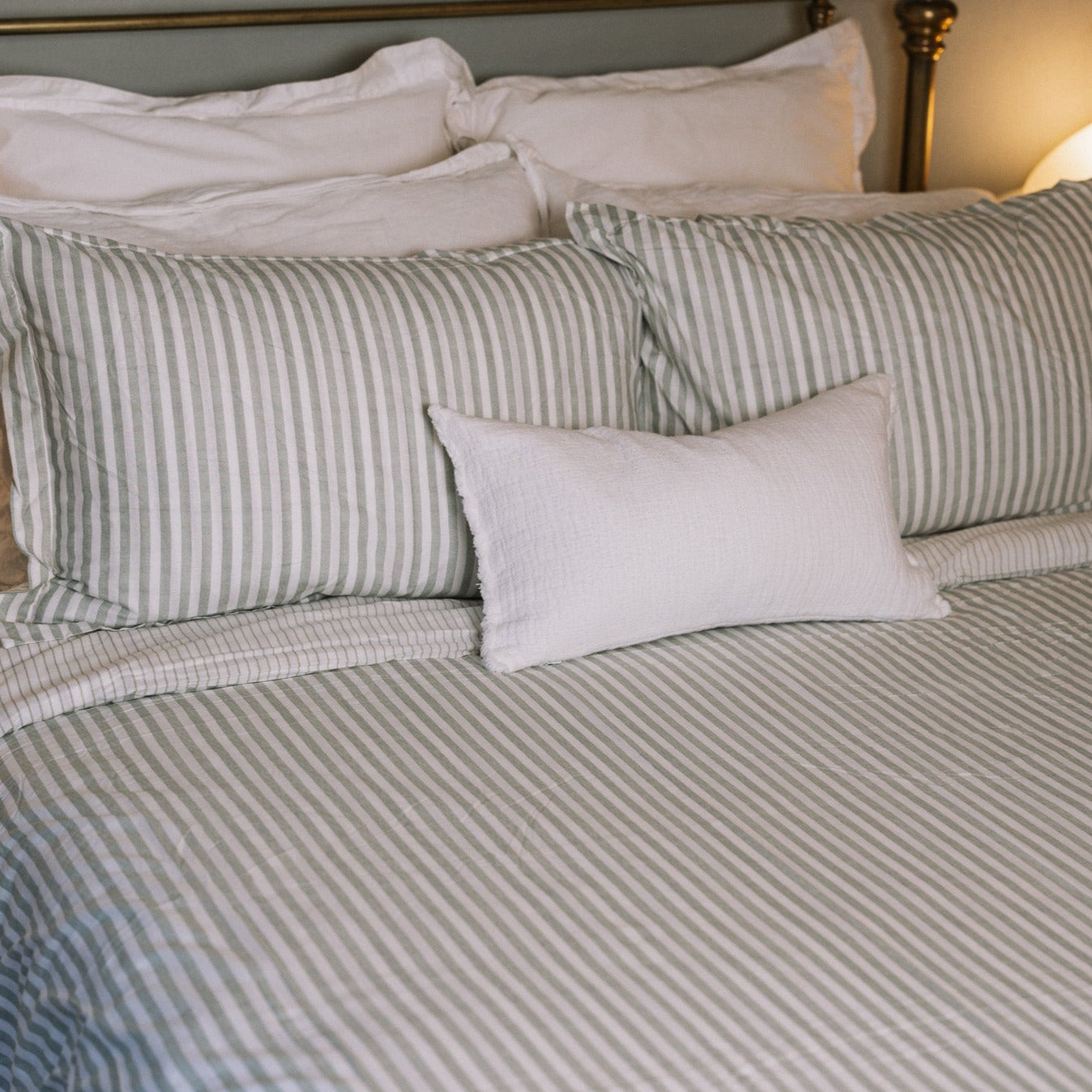 Green striped bedding on a brass bed.