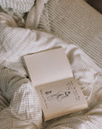 Green striped bedding, unmade with an open book.