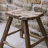 A reclaimed style wooden stool against a stone wall.