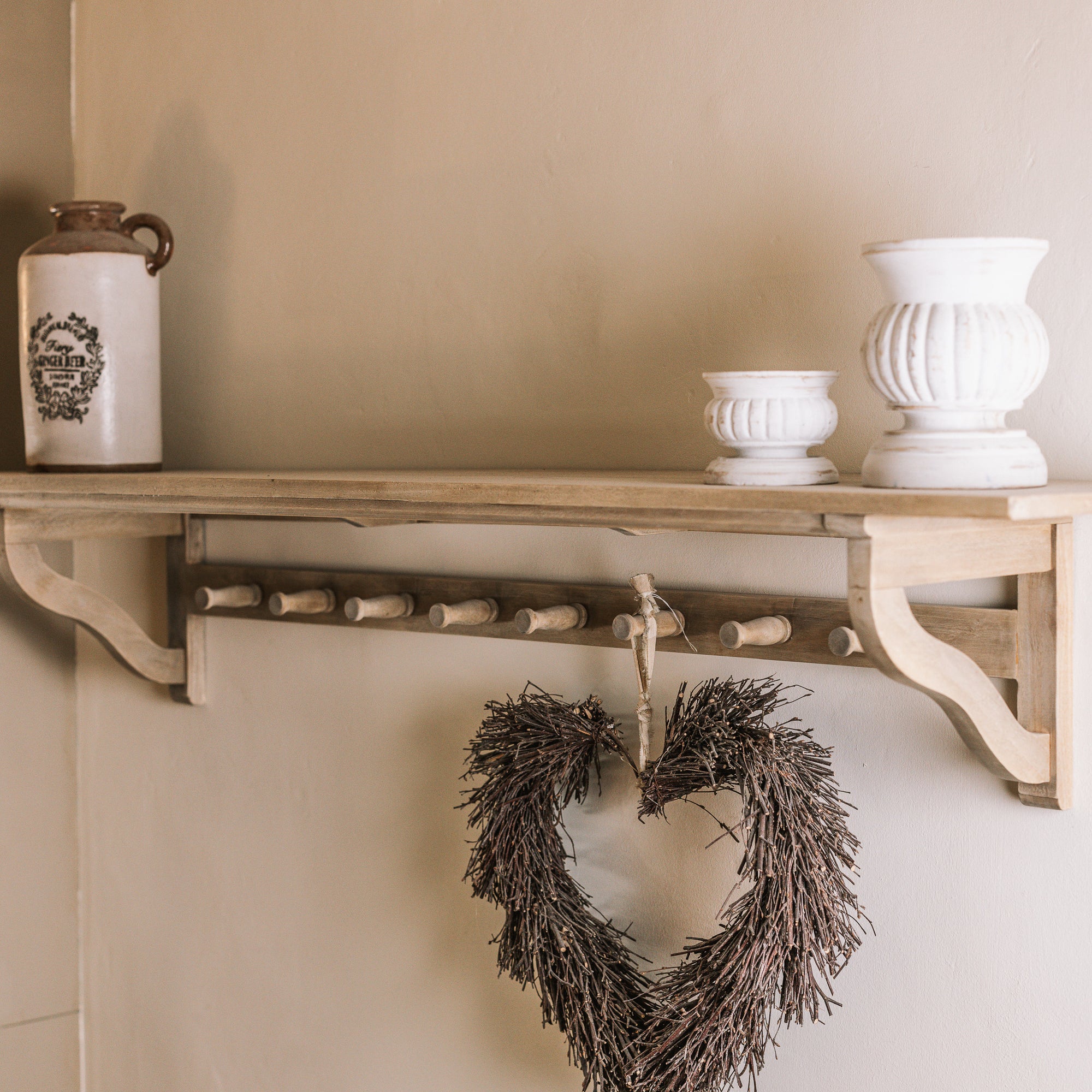 Wooden shelf with coat hooks, decorative items on shelf.