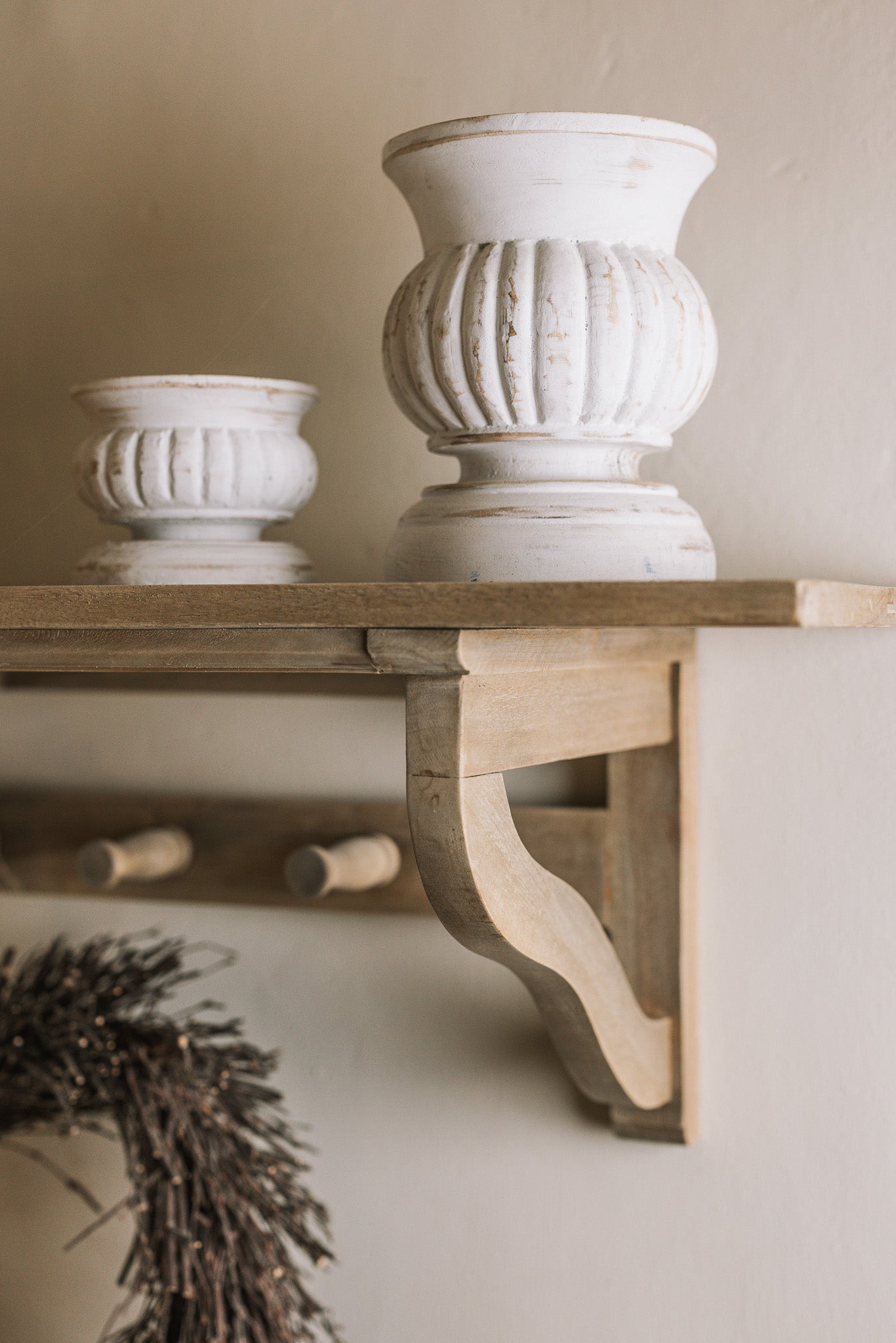 Wooden shelf with coat hooks, decorative items on shelf.