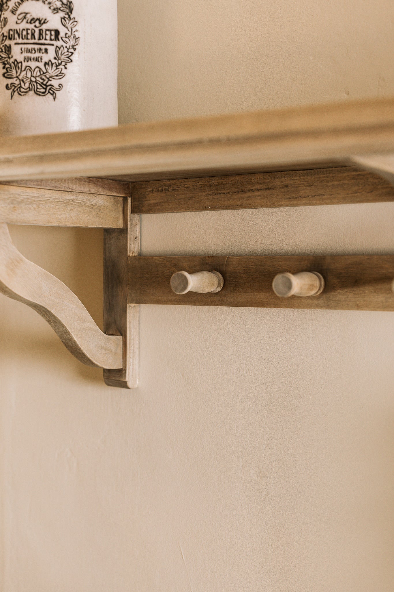 Wooden shelf with coat hooks, decorative items on shelf.