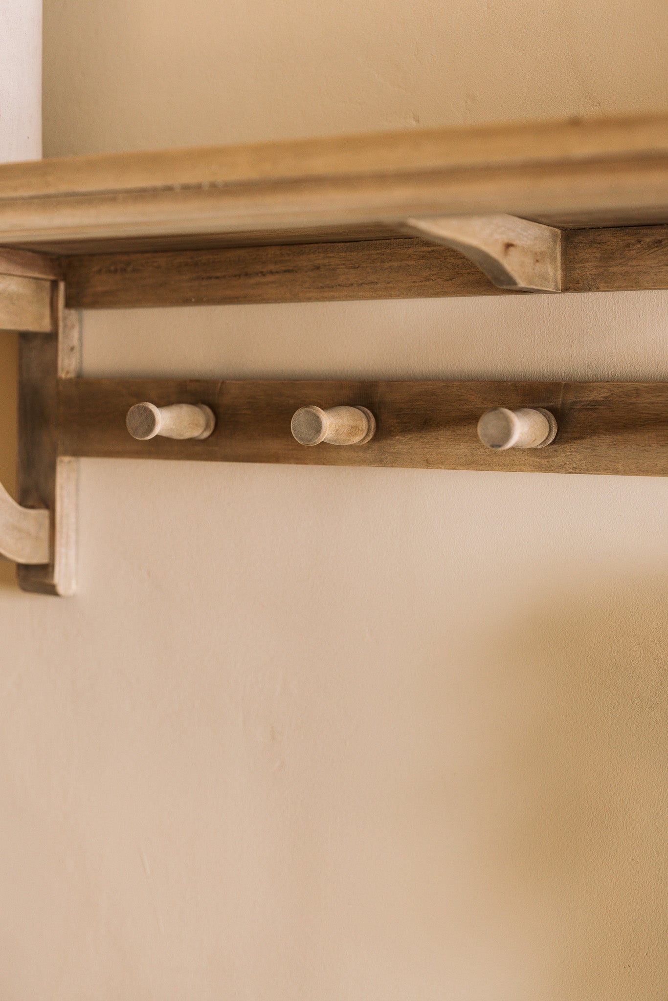 Wooden shelf with coat hooks, decorative items on shelf.