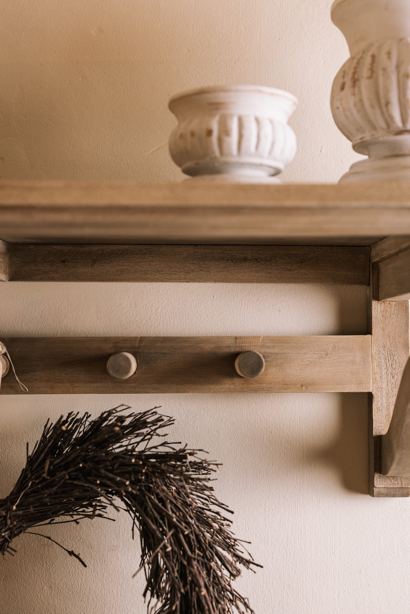 Wooden shelf with coat hooks, decorative items on shelf.
