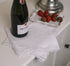 White linen napkin folded over with bobbles on the trim with champagne and strawberries.