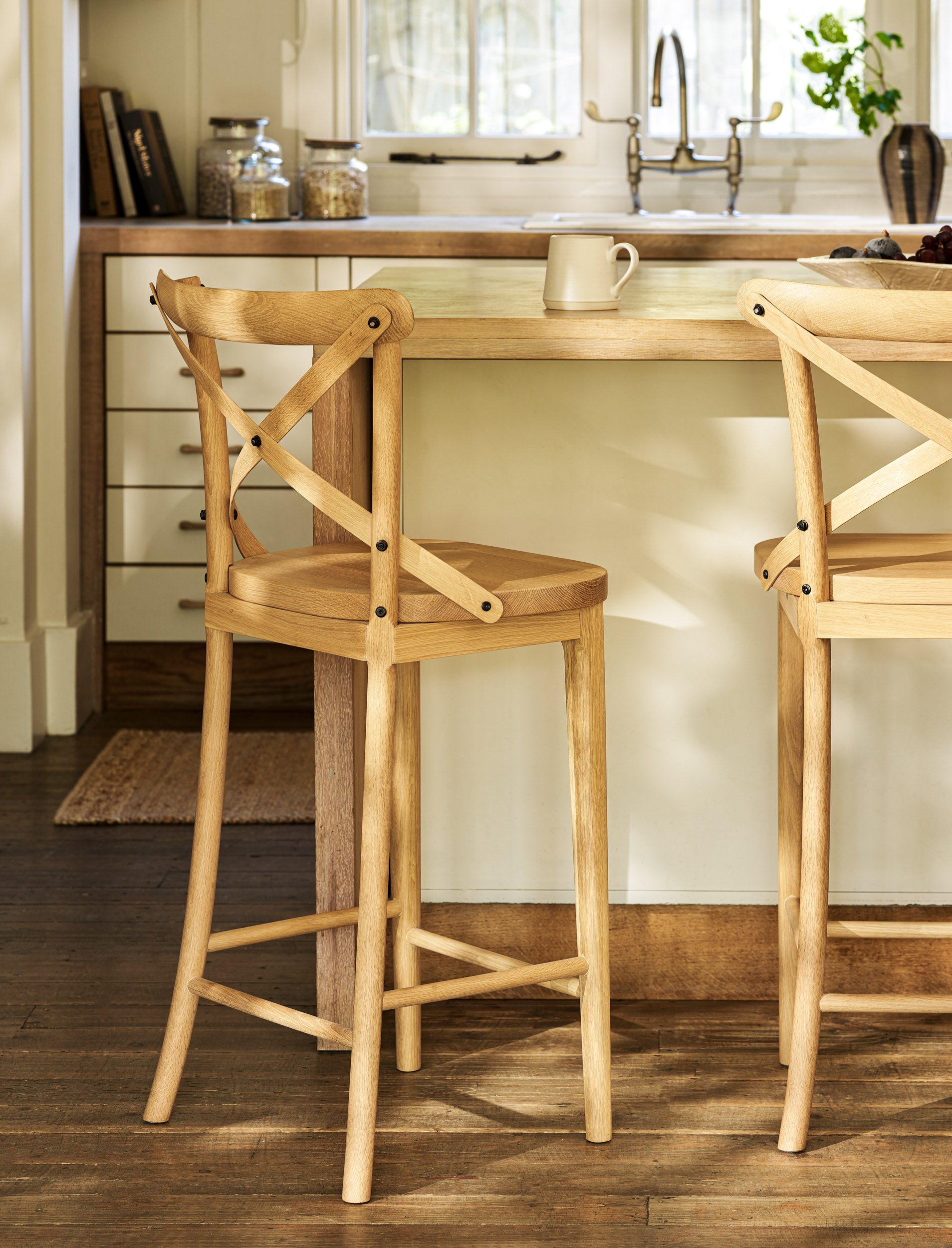 Wooden bar stools in a kitchen setting with a counter and cabinets.