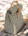 Striped lunch bag with leather straps on a patterned surface