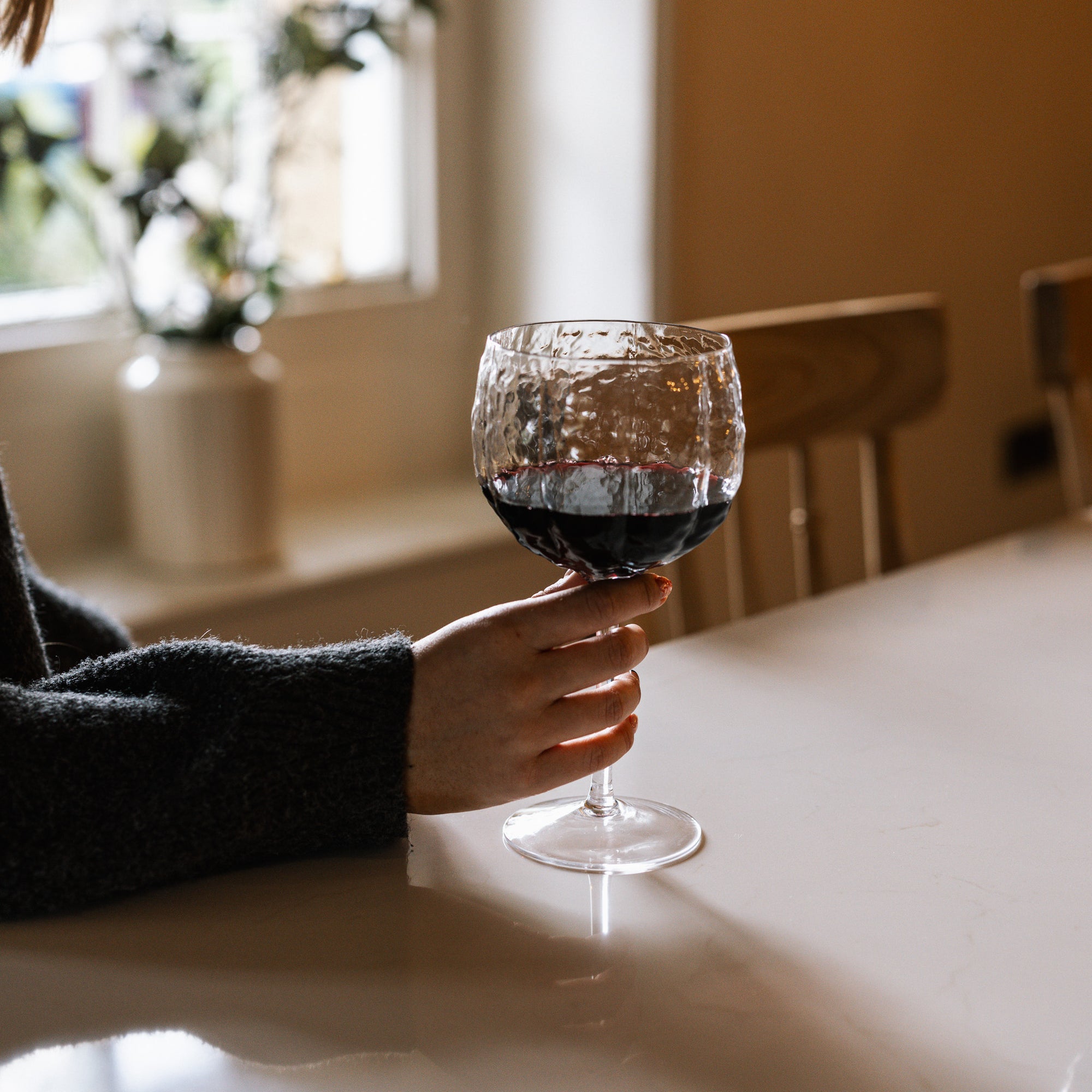 textured red wine glass in a dimly lit kitchen.