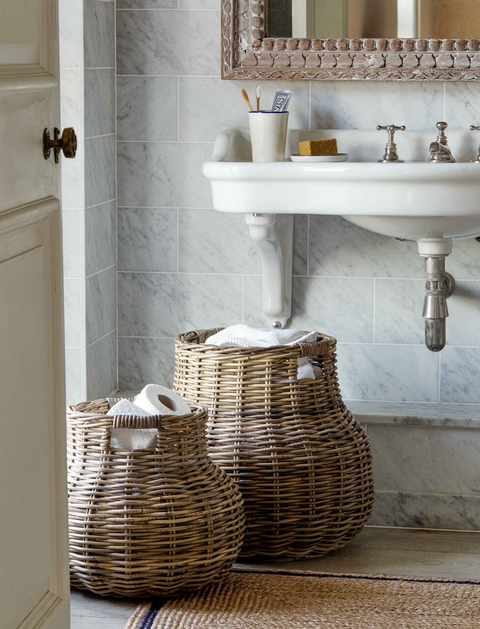 Bathroom with rattan storage baskets, marble tiles, and a sink.