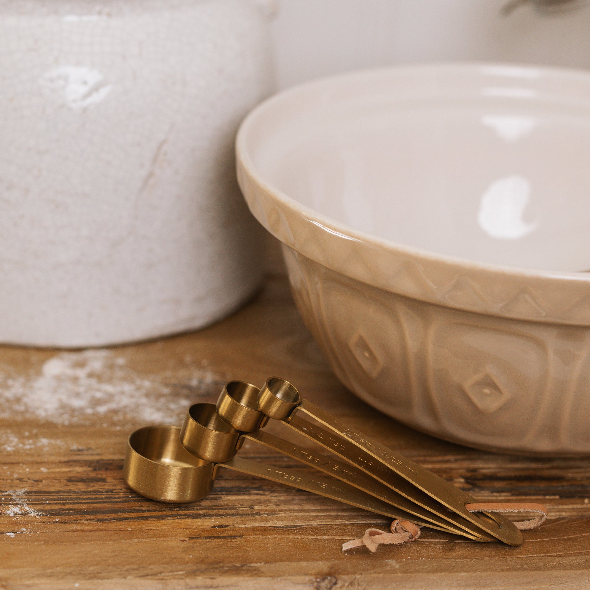 Brass Measuring Spoons next to ceramic mixing bowl.