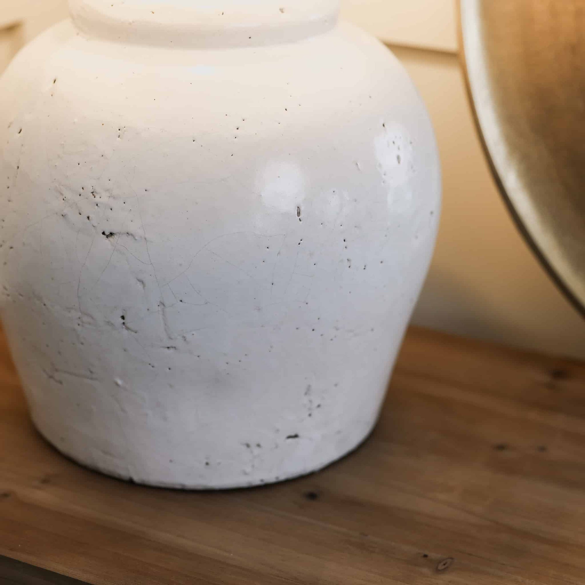 Close up of distressed white lamp base on wooden console.