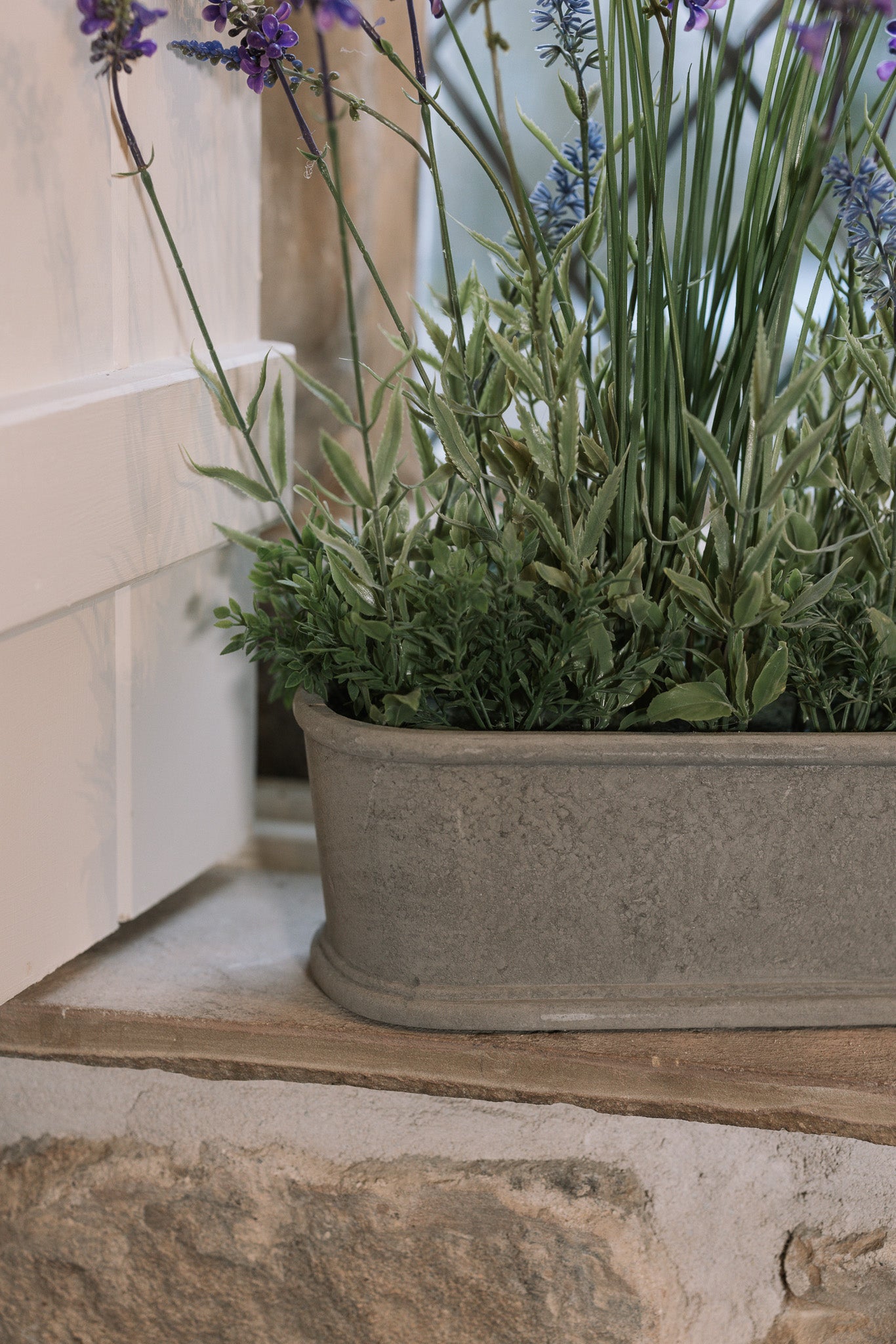 Detailed shot of Faux lavender plant in pot on stone windowsill. 