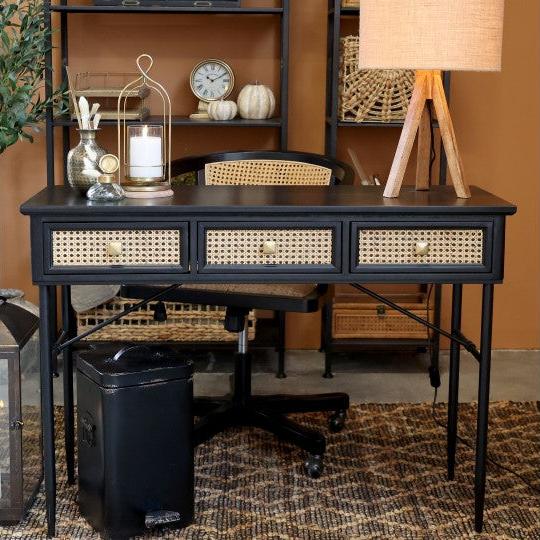 Black and rattan wooden desk with drawers in office.