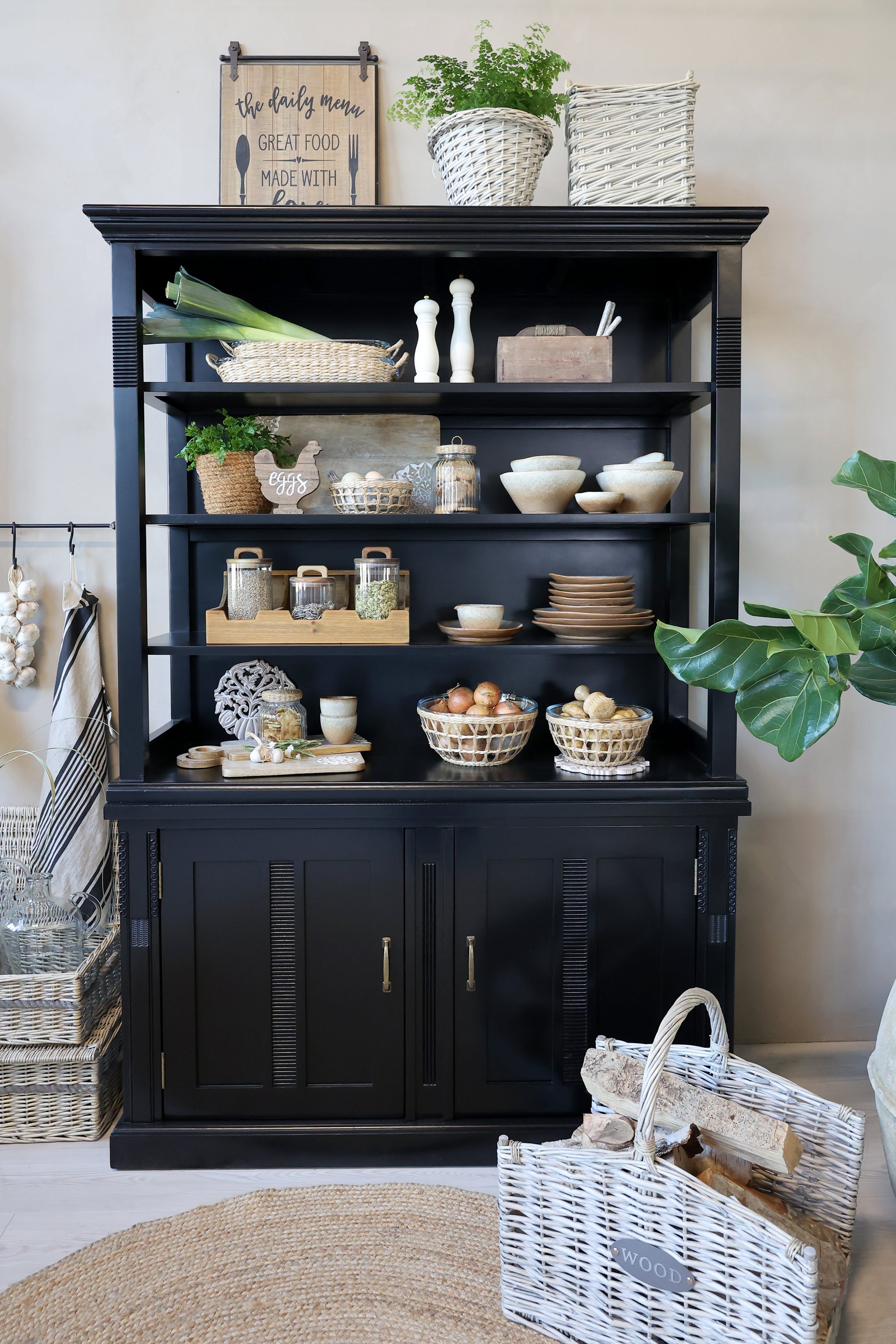 Black shelving unit filled with kitchen crockery, pantry items and farmhouse accessories.